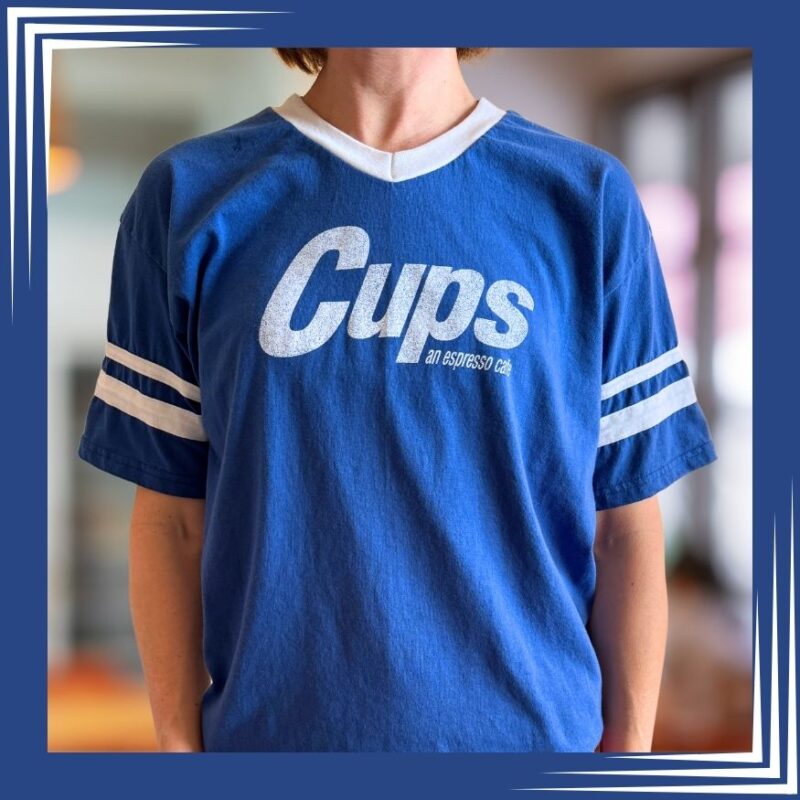 Woman wearing navy blue V-neck Cups t-shirt.